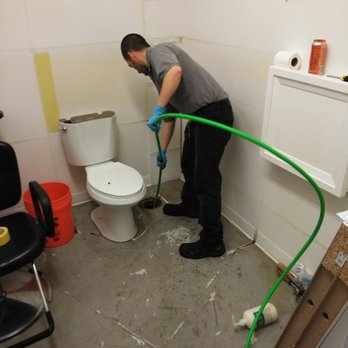 Danika plumber clearing a toilet drain line with a drain machine