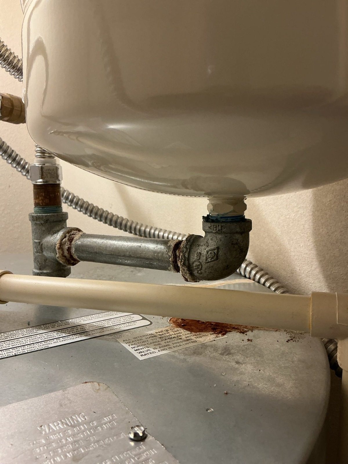 Close-up of corroded, leaking galvanized fittings and rust on top of a water heater in Marysville, WA